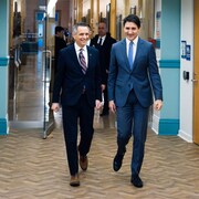 Le maire d'Ottawa, Mark Sutcliffe, et le premier ministre du Canada, Justin Trudeau, marchent ensemble dans les locaux de l'hôtel de ville.
