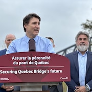 Justin Trudeau en conférence de presse à l'Aquarium du Québec, le pont de Québec en arrière plan.