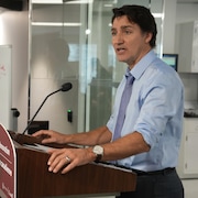 Justin Trudeau debout derrière un micro durant un point de presse.