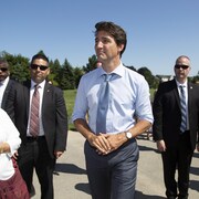 Justin Trudeau marche dehors, entouré de gardes de sécurité.