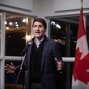 Il est debout devant le drapeau canadien et celui de l'UE.