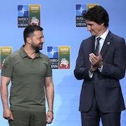 Justin Trudeau applaudit en regardant Volodymyr Zelensky à ses côtés lors d'un sommet de l'OTAN.