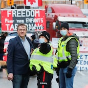 Keith Wilson discutant avec un policier devant des camions stationnés lors d'une manifestation.