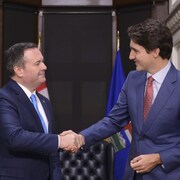 Jason Kenney et Justin Trudeau se serent la main lors d'une rencontre.
