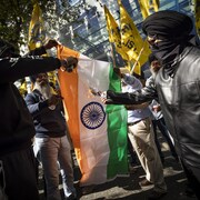 Deux hommes mettent le feu à un drapeau indien.