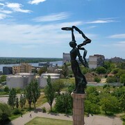 Vue aérienne de la ville, incluant une statue qui la surplombe. Des véhicules militaires sont visibles. 
