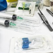 Une trousse médicale d'urgence avec ciseaux, seringues, ruban adhésif, gaze et autres éléments.