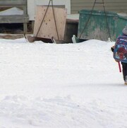 Un enfant marche dans la neige avec son sac d'école.