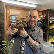 Tommy St-Laurent pose pour la caméra en tenant une tortue dans ses mains.