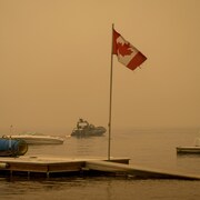 Un bateau de la GRC navigue sur le lac Shuswap sous une épaisse fumée en provenance du feu Adams Lake, en Colombie-Britannique.