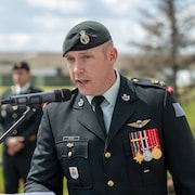 Un officier supérieur de l'armée canadienne se tient devant un microphone.