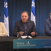 François Legault, entouré de Sonia LeBel et de Bernard Drainville lors d'une conférence de presse.