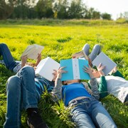 Une famille allongée dans l'herbe, chacun dévorant un livre.