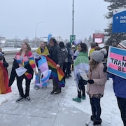 Sur le trottoir, à l'extérieur de l'école, des jeunes de l'école secondaire de Leduc manifestent contre les mesures proposées par Danielle Smith sur l'identité de genre. 