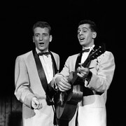 Dans un studio de télévision, les deux hommes chantent, l'un d'eux s'accompagnant à la guitare.