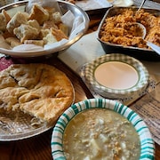 Une table sur lequel est déposé un pâté de viande, une soupe, un bol de pain et ce qui ressemble à de la jambalaya. 
