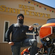 Un motard pose avec sa moto devant le temps Sikh de Paldi,