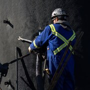 Deux personnes en bleu de travail sont en train de nettoyer un ancien puits de pétrole, à Frog Lake en Alberta, au mois d'octobre 2022.