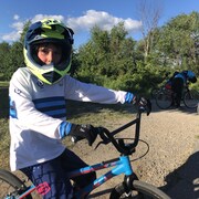 Liam Brulé pose pour la caméra sur son BMX.