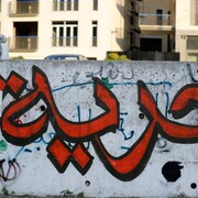 Un graffiti représentant une calligraphie arabe peinte en rouge et noir.