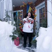 Une femme joint ses mains et sourit en regardant la neige.