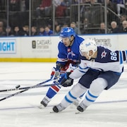 L'ailier gauche des New York Rangers Artemi Panarin patine contre le défenseur des Winnipeg Jets Nate Schmidt pendant la deuxième période d'un match de hockey de la LNH.