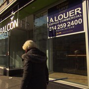 Une femme passe devant un local commercial vacant à Montréal.