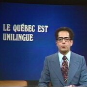 Le présentateur Paul-Émile Tremblay anime le Téléjournal; à l'arrière, l'inscription « Le Québec est unilingue ».