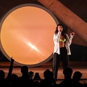 La chanteuse Lorde chante sur une scène devant une foule assise.