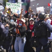 Des gens manifestent devant les policiers dans le centre de Los Angeles le dimanche 8 juin 2025.