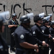 Des policiers du LAPD font face à des manifestants près d'un graffiti anti-ICE, le 9 juin 2025, à Los Angeles, en Californie.