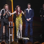 Une femme brandit un troph&eacute;e sur sc&egrave;ne.