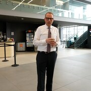 Louis Blouin est debout dans l'atrium de Radio-Canada à Montréal. 