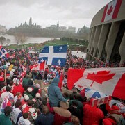 Des centaines de personnes brandissant des drapeaux du Québec et du Canada.