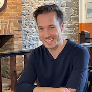 Luc Langevin assit à une table de restaurant devant un mur de brique.