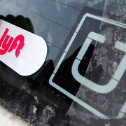 Autocollants avec le logo de Lyft et d'Uber sur un pare-brise. 