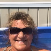 Gros plan du visage d'une femme qui porte des lunettes fumées et qui est dans une piscine à l'extérieur.