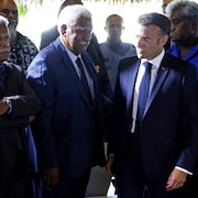 Le président français Emmanuel Macron entouré de plusieurs hommes.