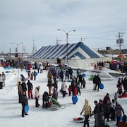 Des dizaines de personnes s'activent autour d'un chapiteau au centre-ville d'Amos, l'hiver.