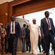 Le général Mahamat Déby entre dans une salle entouré de militaires et de gardes du corps en saluant la foule, le 2 mars 2024.