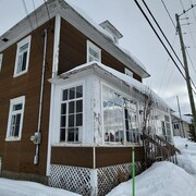 La maison de deux étages avec son papier brique et la véranda vitrée, en hiver.