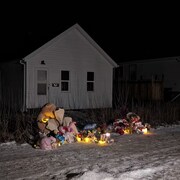 Des fleurs, des bougies et des peluches près d'une maison à Carman, au Manitoba.