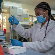 Une technicienne de laboratoire tient une pipette.