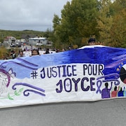 Des gens tiennent une bannière où est écrit « Justice pour Joyce ».