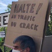 Un homme brandit une pancarte sur laquelle on peut lire : Halte au trafic du crack!