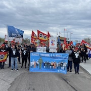 Un groupe d'employés en grève manifestent avec des pancartes et banderoles.