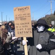 Des manifestants tiennent des pancartes contre les drag queens dans les éécoles et les bibliothèques.