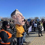 Une manifestation à McMasterville, le 4 février 2024, avec de nombreux manifestants, dont un qui porte une tête géante de François Legault.