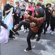 Une jeune personne dans la rue donne un coup de pied sur un drapeau bleu et rose.