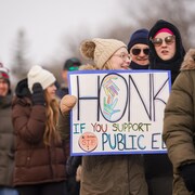 Un groupe de personnes manifeste avec des membres de la Fédération des enseignants de la Saskatchewan (STF) devant le Palais législatif de la Saskatchewan, le 20 mars 2024.